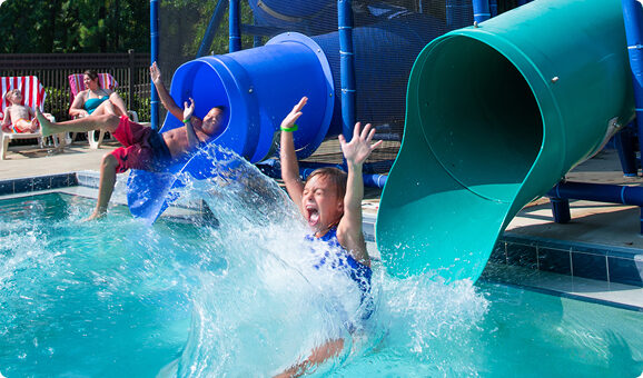 Girl sliding out of a tube into the swimming pool